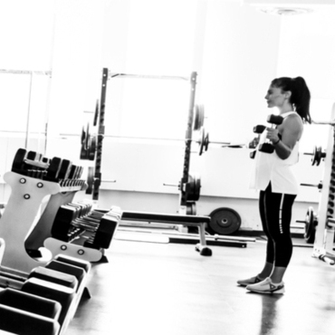Personal training patron looks in mirror while lifting weight