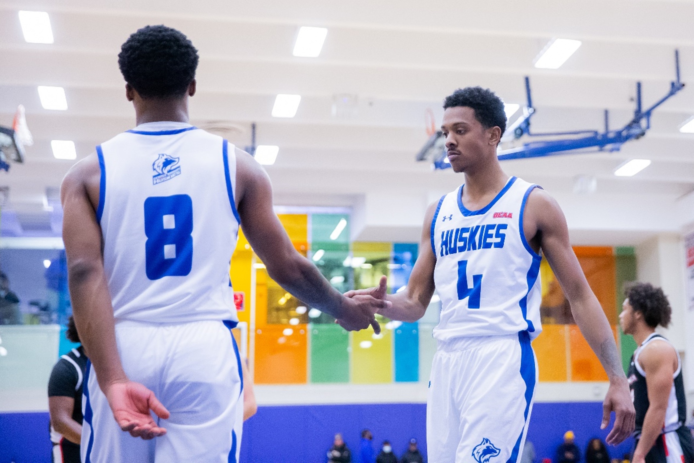 Two Huskies players low-five each other
