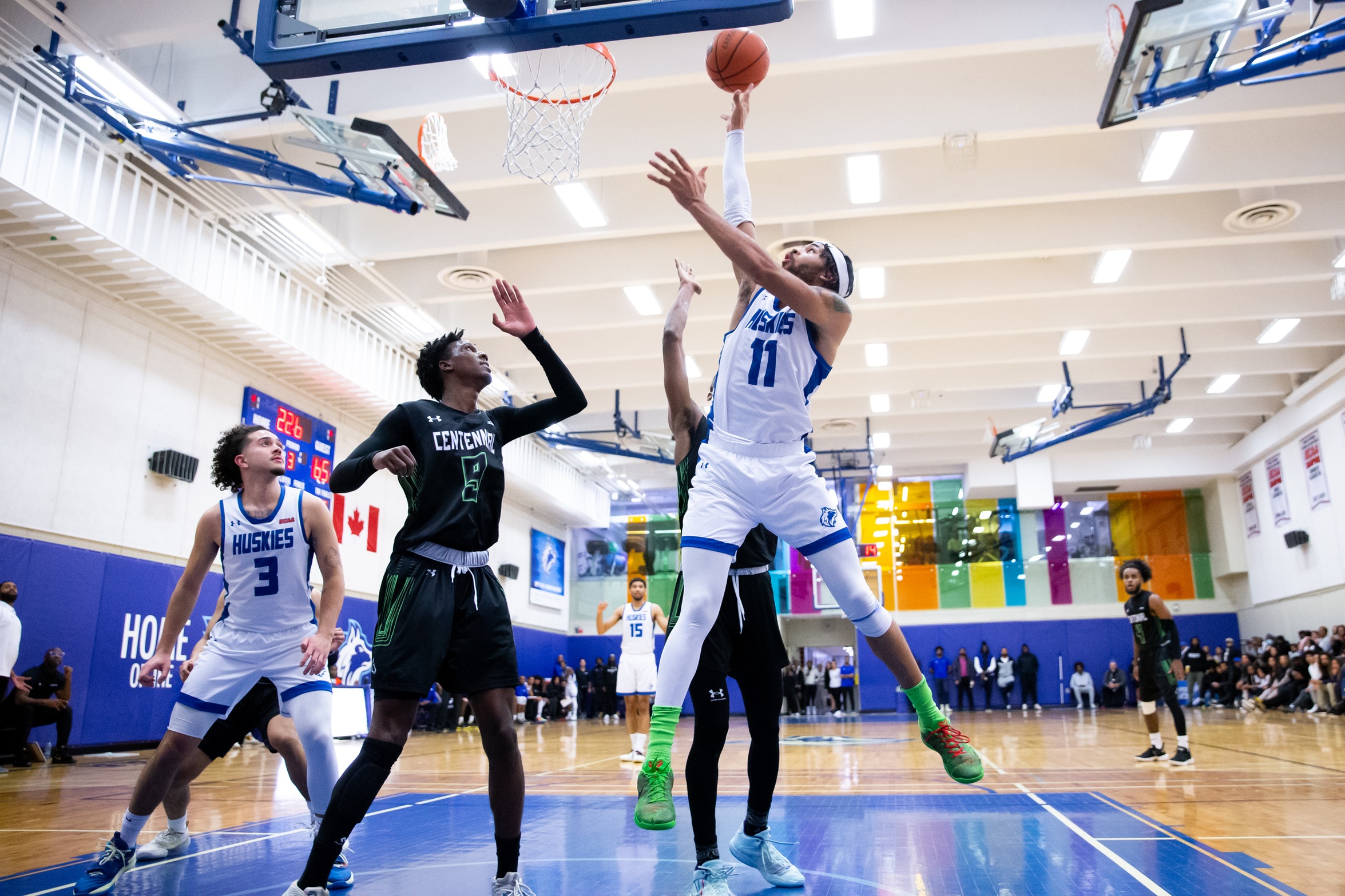 Huskies #11 goes up for layup between two Colts players