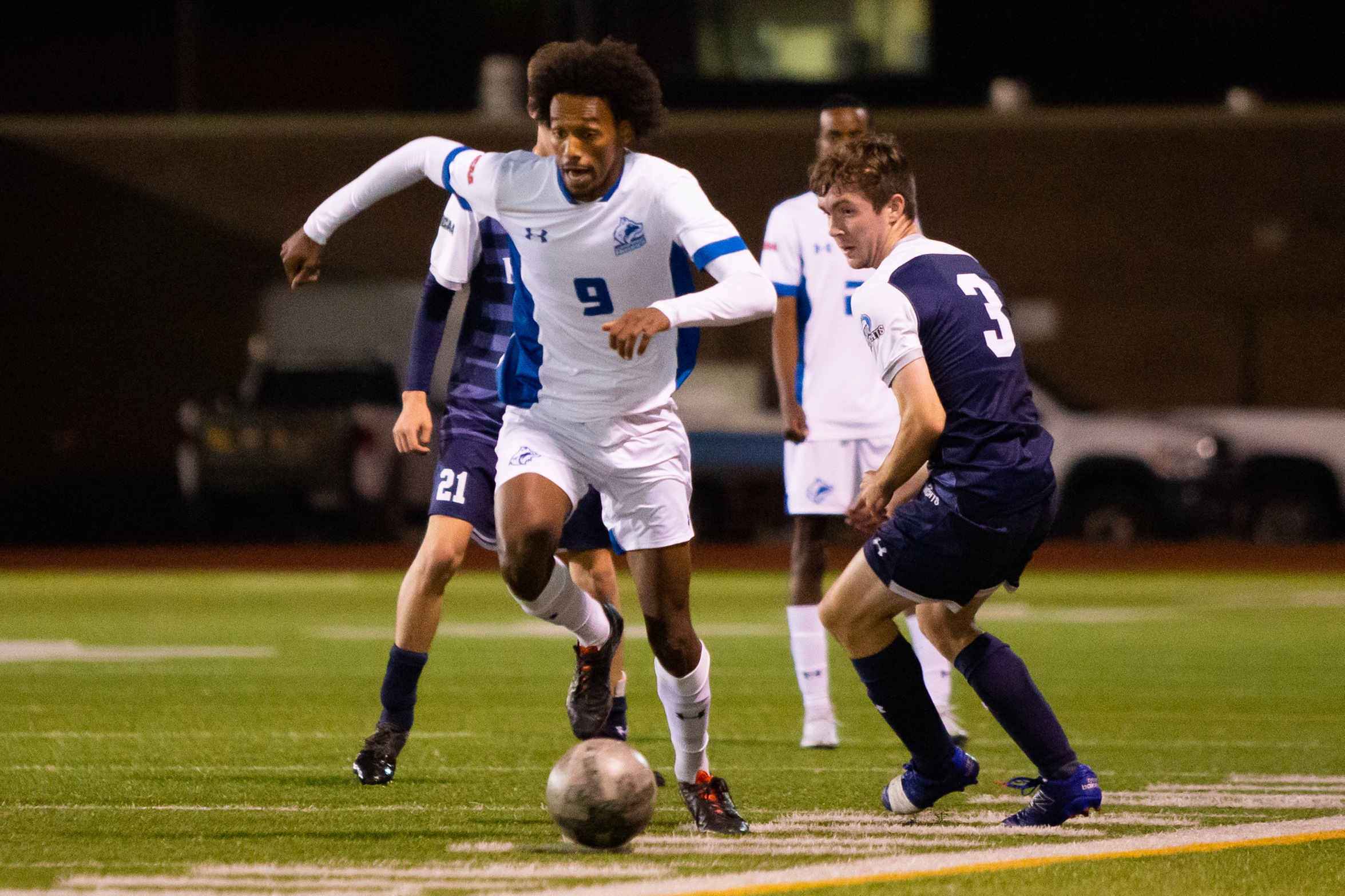 Huskies #9 dribbles soccer ball past defender