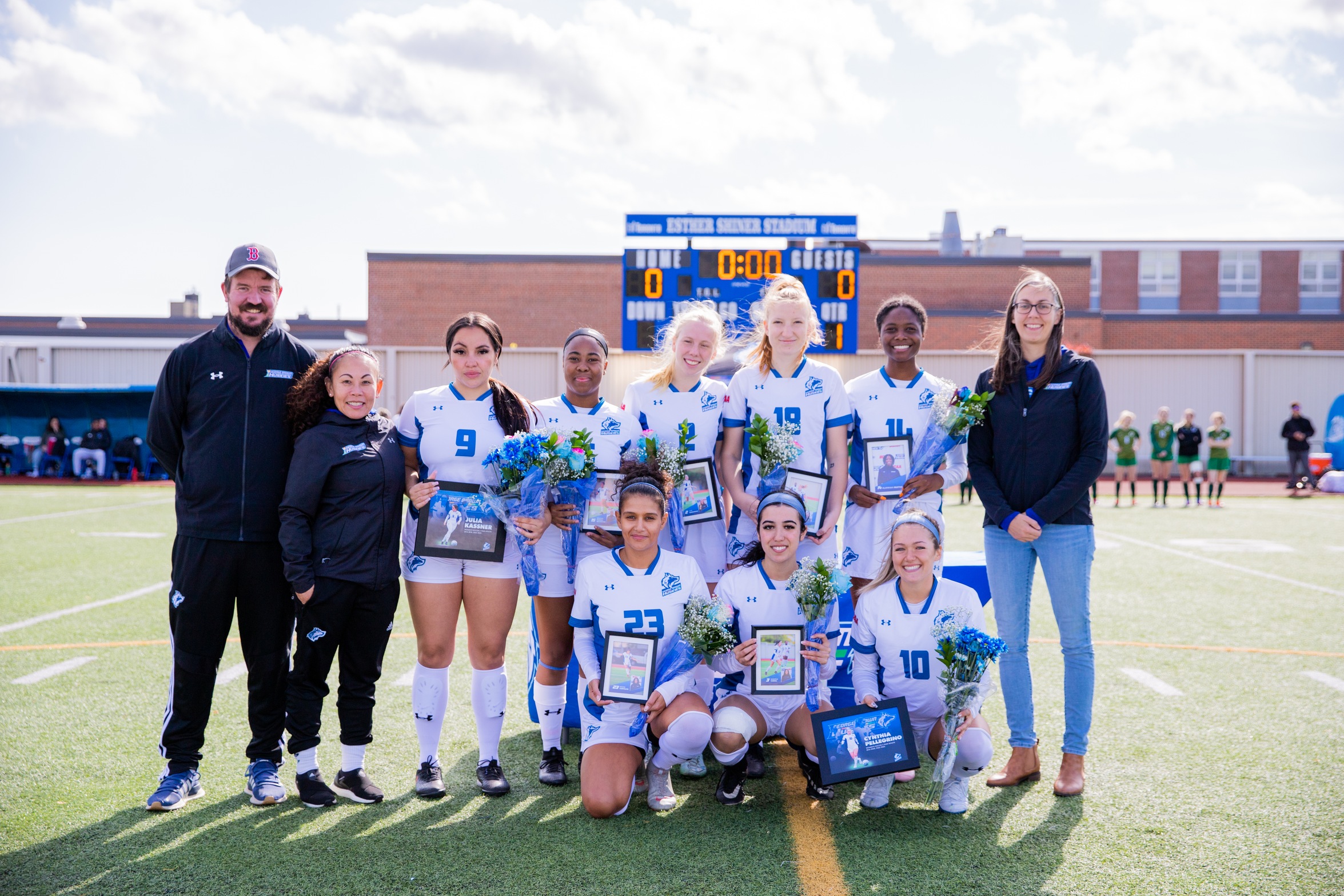 Huskies graduating player photo, all grads in two lines with coaches holding flowers and framed photos.
