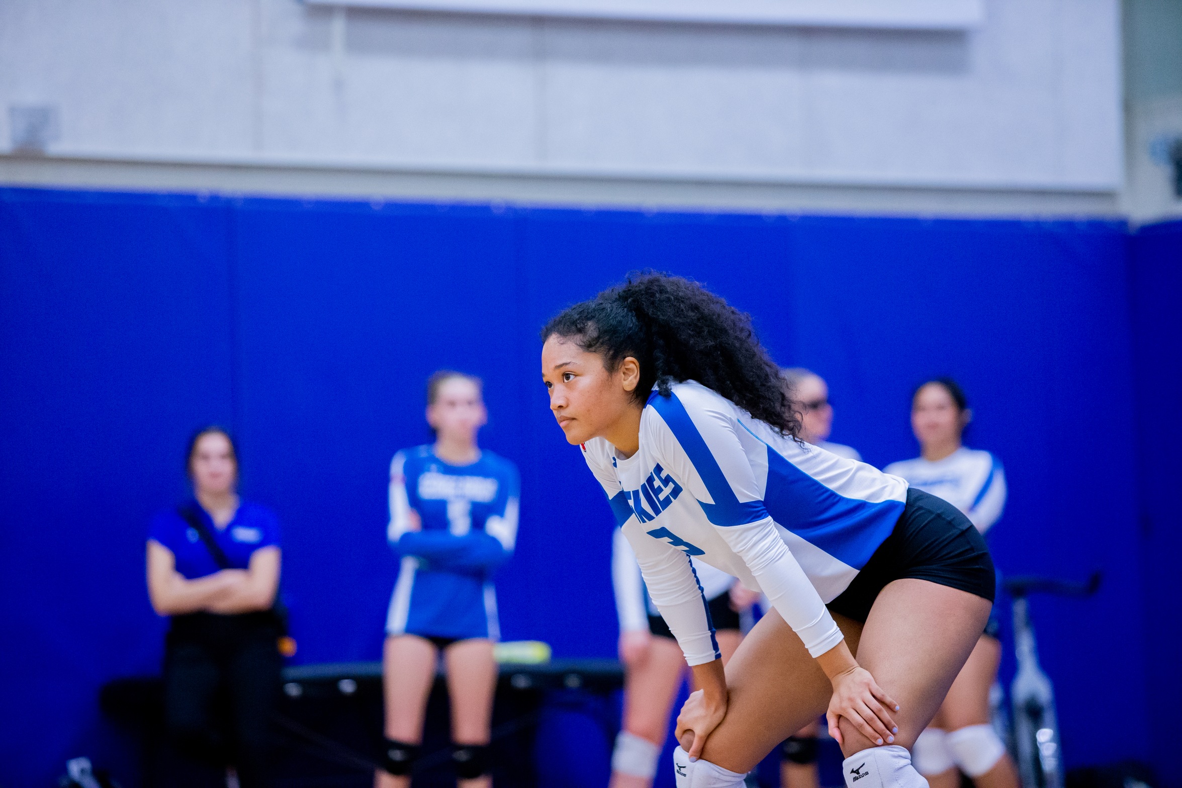 Huskies volleyball players leans with hands on knees waiting for serve